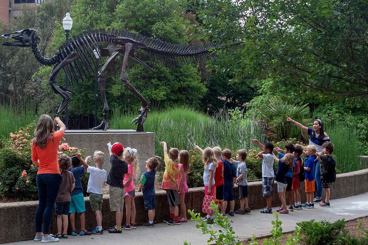 Group of students looking at dinosaur outside